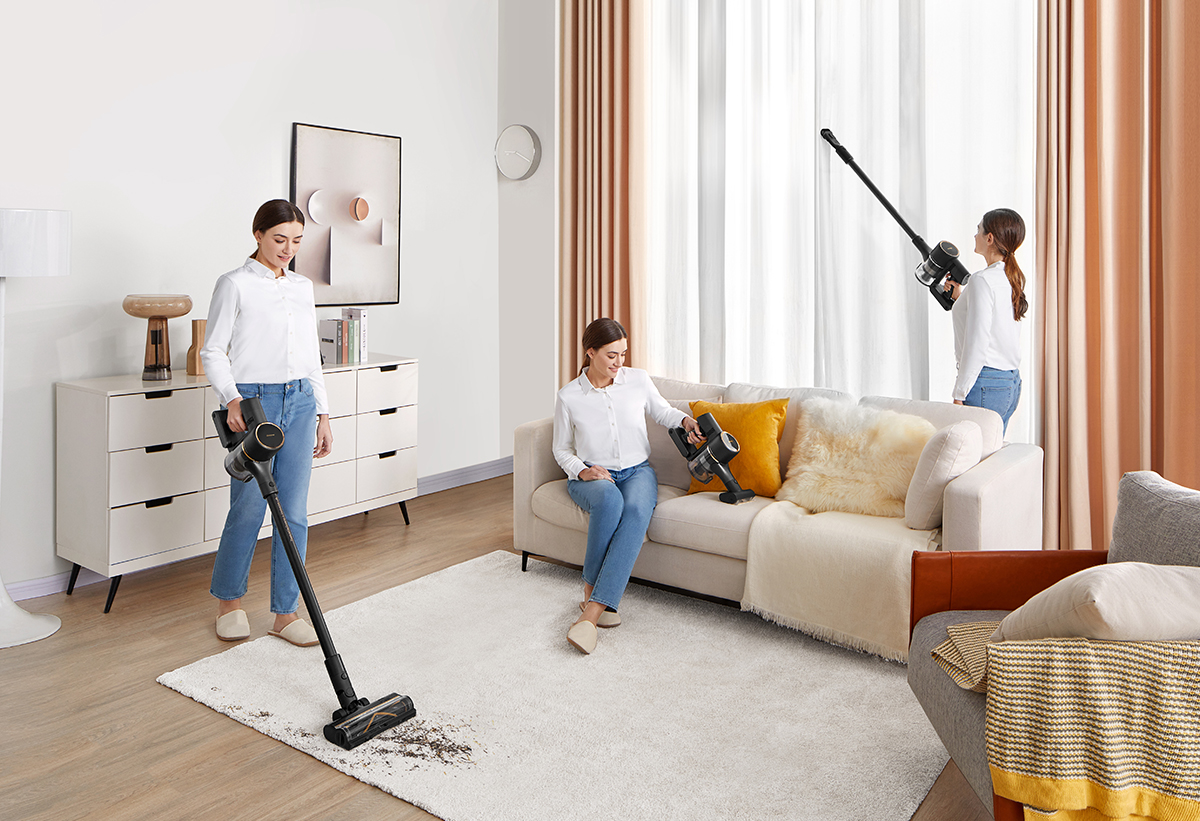 Απεικονίζεται μια γυναίκα να καθαρίζει με τη σκούπα ένα χαλί, έναν καναπέ και μια κουρτίνα, χρησιμοποιώντας κάθε φορά και άλλο εξάρτημα.